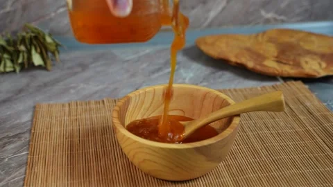 A chef pours ready-made cloudberry jam into a deep wooden bowl. Video stock 305582022