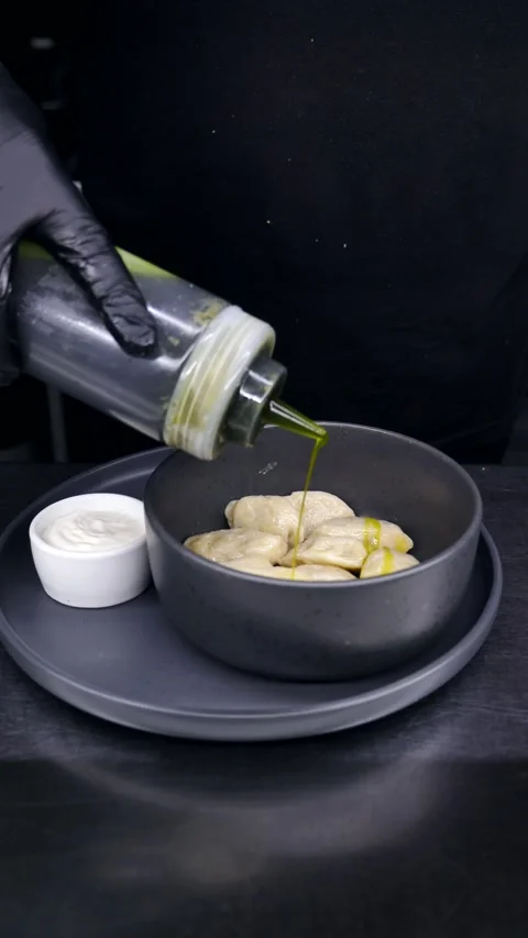 Chef pours sauce over dumplings. Serving the finished dish. Restaurant menu Stock Footage 309279210