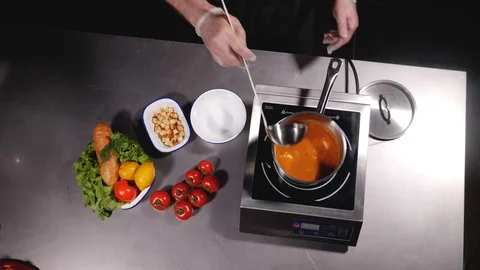 A chef pours soup into a bowl, throws pieces of croutons and puts a dill. Stock Footage 127959646