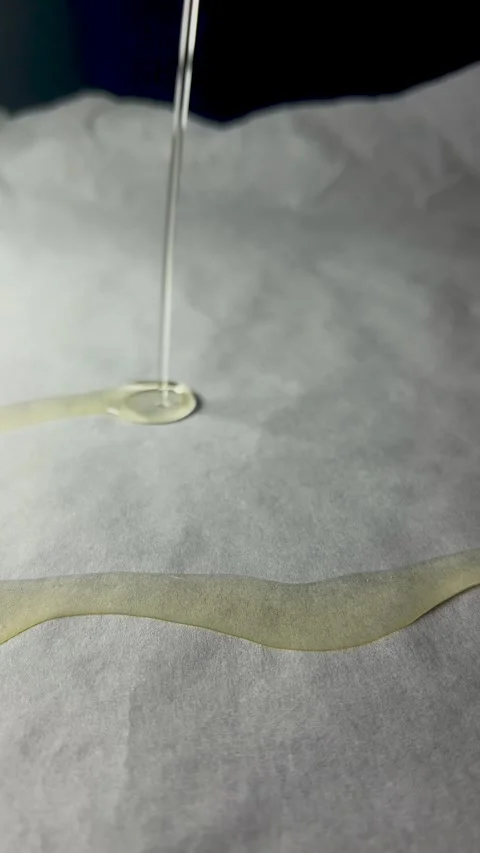 Chef pours vegetable oil onto baking paper. Liquid flows down parchment Stock Footage 283854110