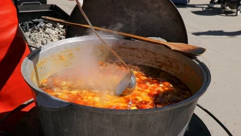 Chef pours winter soup from a large cast-iron cauldron.  Street food festival Stock-Footage 107506675