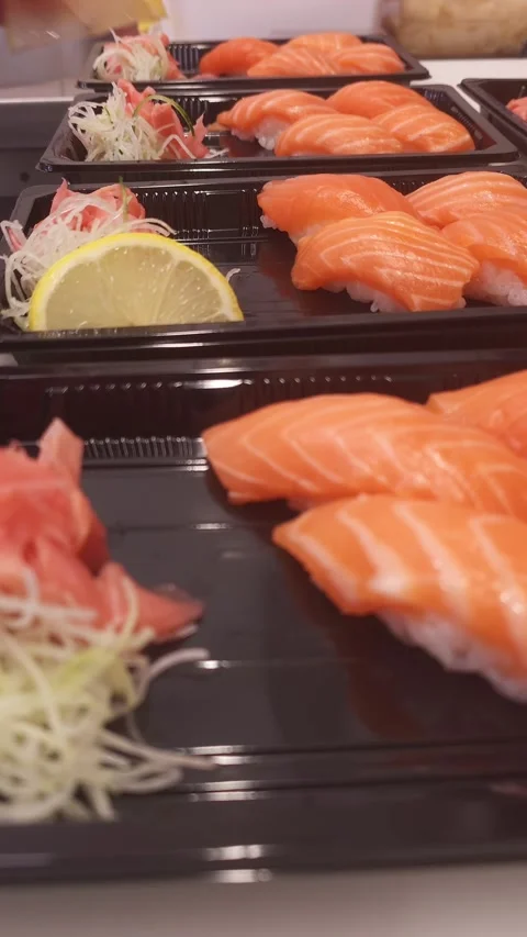Chef precisely arranges lemon slices over salmon nigiri sushi adding a citrus Stock Footage 285656542