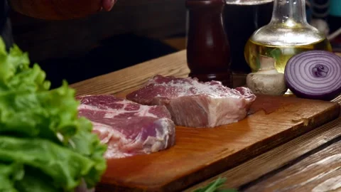 The chef prepares a beef steak sprinkled with salt. Stock Footage 197489402