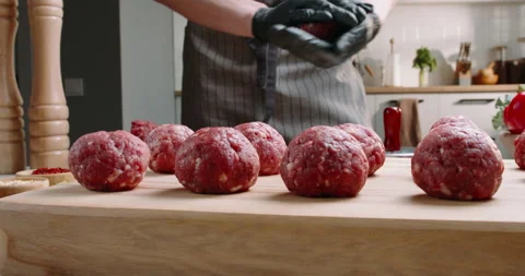 Chef prepares blanks for meatballs from fresh minced meat in a kitchen with Stock Footage 245519320