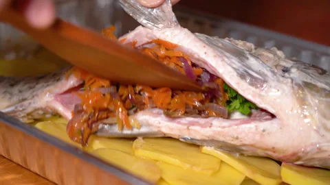 Chef prepares carp for baking, puts vegetables inside Stock Footage 248529443