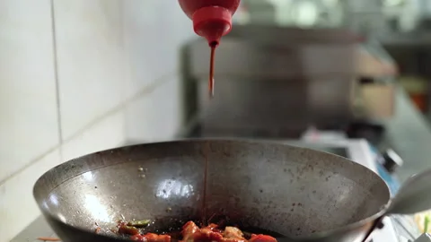 The chef prepares chicken in a large wok. Adds soy sauce to the dish. Stock Footage 150499627