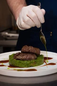 The chef prepares chops with spinach before serving the dish Stock Photos