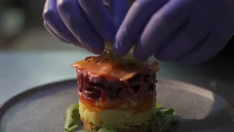 Chef prepares diet lunch in kitchen. puts slices greenery on plate salad Video stock 303554748