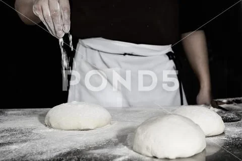 Chef prepares the dough with flour to make a pizza. Stock Photos