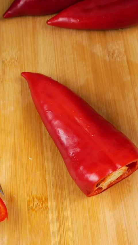 A chef prepares a fresh sweet red pepper on a wooden cutting board. Video stock 341527283