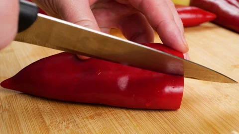 A chef prepares a fresh sweet red pepper on a wooden cutting board. 库存影片 341527345