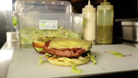 The chef prepares a hamburger in the kitchen at a fast food restaurant. Stock Footage 208380950