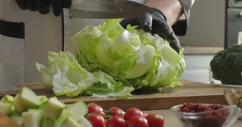 Chef prepares healthy salad, cuts lettuce on the cutting board. Male chef Stock Footage 277760068