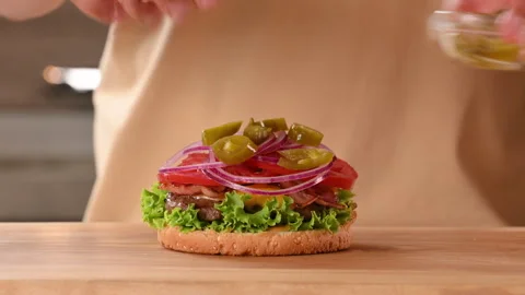 The chef prepares a meat burger with a cutlet, cheese and vegetables. Stock Footage 296071698