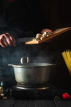 The chef prepares soup on the background of vegetables and spaghetti. Stock Photos