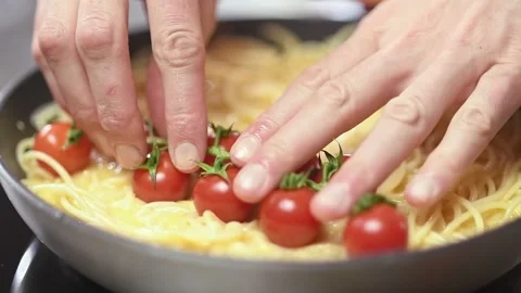 Chef prepares spaghetti frittata with cherry tomatoes in a pan. Stock-Footage 151046031