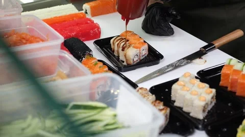 The chef prepares sushi, pouring with sauce, before serving. Stock Footage 323911468