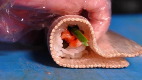 Chef prepares sushi with red fish, cucumbers, nori in kitchen in restaurant Stock Footage 269544725