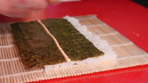 Chef prepares sushi with red fish, cucumbers, nori in kitchen in restaurant Vidéo 269544886