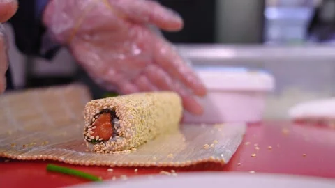 Chef prepares sushi with red fish, cucumbers, nori in kitchen in restaurant Видео 269569380
