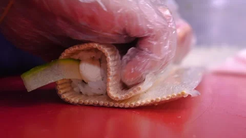 Chef prepares sushi with red fish, cucumbers, nori in kitchen in restaurant Stock Footage 269572150