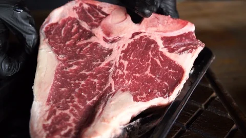The chef prepares T-bone steak in his restaurant. He takes out a large piece of Video stock 107674113