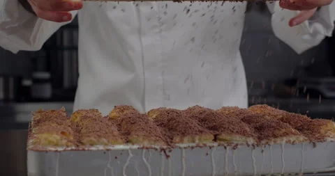 Chef prepares Turkish cold baklava. Pastry chef sieves shredded chocolate Stock Footage 281518916