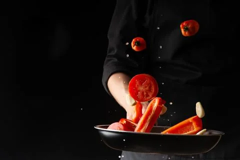 Chef prepares vegetables, roasting on a griddle on a black background, horizo Stock Photos