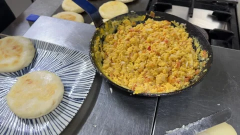 Chef preparing and filling traditional arepas with scrambled eggs 스톡 동영상 344100170