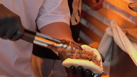 Chef preparing bao buns with pulled pork, vegetables, and sauce Stock Footage 313674634