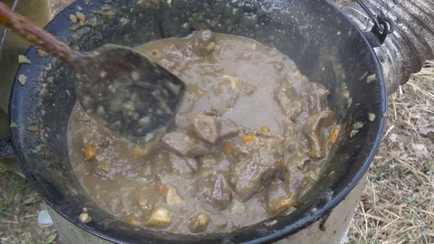 Chef preparing beef goulash mixing with wooden spoon in boiler, close up. Stock Footage 81542800