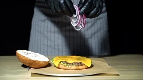 Chef preparing the burger. Close up hands of man throwing ring onion Stock Footage 112367082