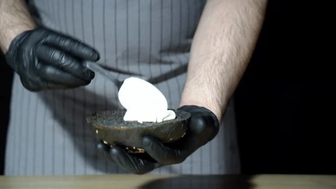 Chef preparing the burger. Cook's hands applying cream sauce on black burger Stock Footage 113613176