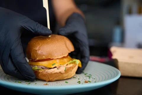 Chef preparing burger on plate for serving Stock Photos
