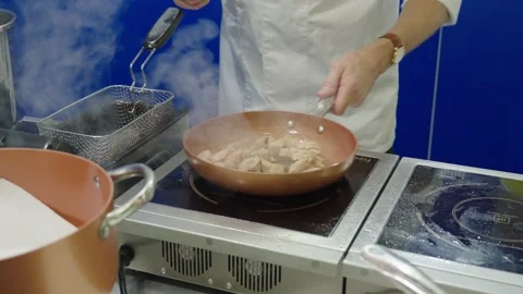 Chef preparing chicken meat pieces on electric stove Stock Footage 304317363