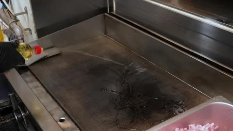 Chef preparing a commercial flat top grill by oiling the surface with cooking oi Stock Footage 331636362