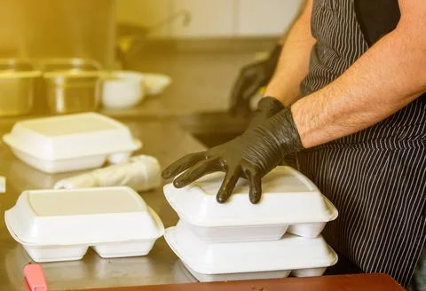 Chef preparing dish to a box in the restaurant for food delivery service to home Stock Photos