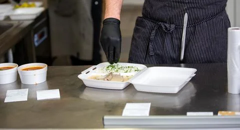 Chef preparing dish to a box in the restaurant for food delivery service to home 库存照片