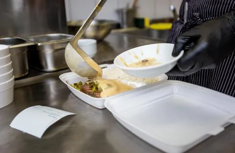 Chef preparing dish to a box in the restaurant for food delivery service to home Stock Photos