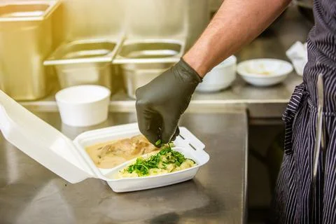 Chef preparing dish to a box in the restaurant for food delivery service to home Stock Photos