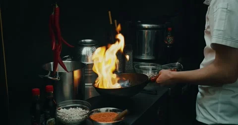 Chef preparing a dish in a frying pan. Oil and alcohol ignite with open flame Stock Footage 139129075