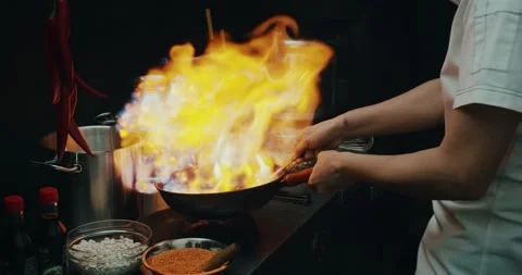 Chef preparing a dish in a frying pan. Oil and alcohol ignite with an open flame Stock Footage 139129144