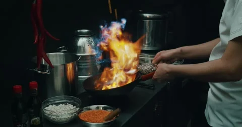 Chef preparing a dish in a frying pan. Oil and alcohol ignite with open flame Stock Footage 139129233