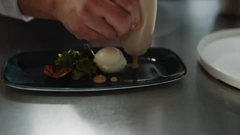 A chef is preparing a dish with a sauce on a plate Video stock 295993968