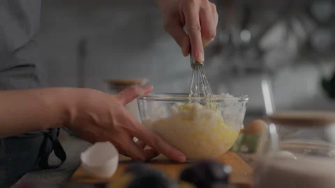 The chef is preparing dough in large glass bowl, combining ingredients with Stock Footage 253890300