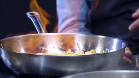 Chef Preparing Flambe Style Dish on a Pan. Close-Up Flaming Pan in Slow Motion Stockbeeldmateriaal 150590580