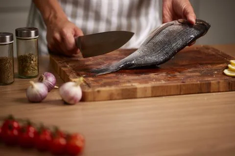 Chef preparing fresh fish using kitchen knife Stock Photos