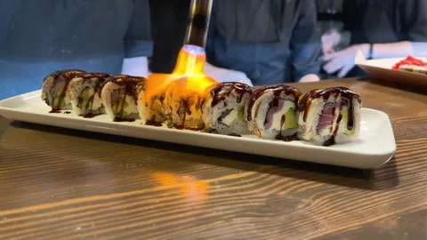Chef preparing hand burning healthy sushi roll on open kitchen counter bar in 스톡 동영상 234812047
