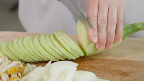 The chef is preparing a healthy dish, cutting zucchini into circles with Stock Footage 270147178