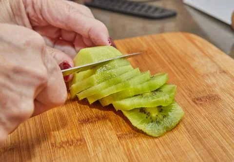 Chef is preparing kiwi pie, cut the kiwi into slices Stock Photos